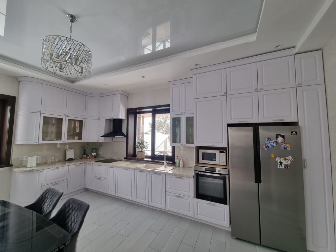 Неоклассическая кухня с белыми фрезерованными фасадами и большой системой хранения - фото - 1