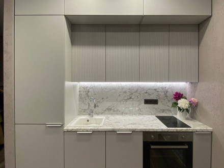 Белая встроенная кухня с антресолями и рифлеными фасадами - фото - 1